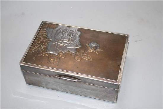 A Japanese silver, copper and gold cigarette box, Meiji period, decorated with a panel of roses, signed, 22 x 14.5cm, height 8cm